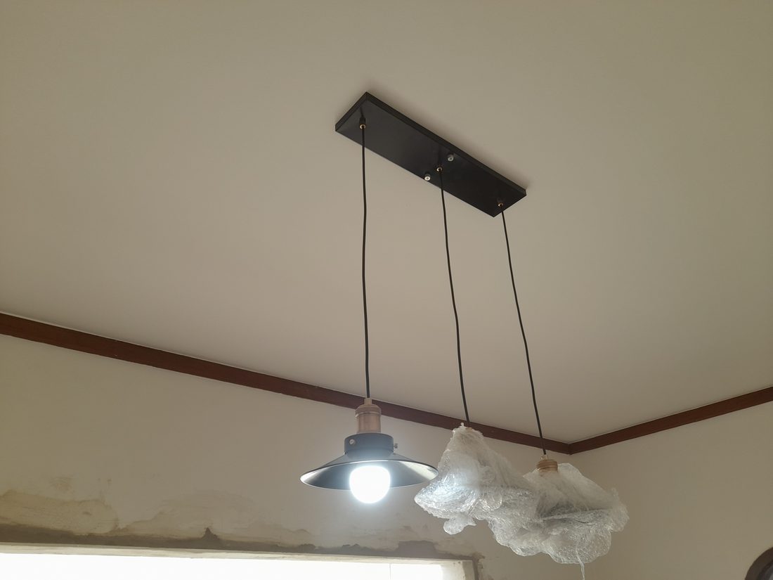 Instalação de luminária tripla, com pendentes em fase de montagem