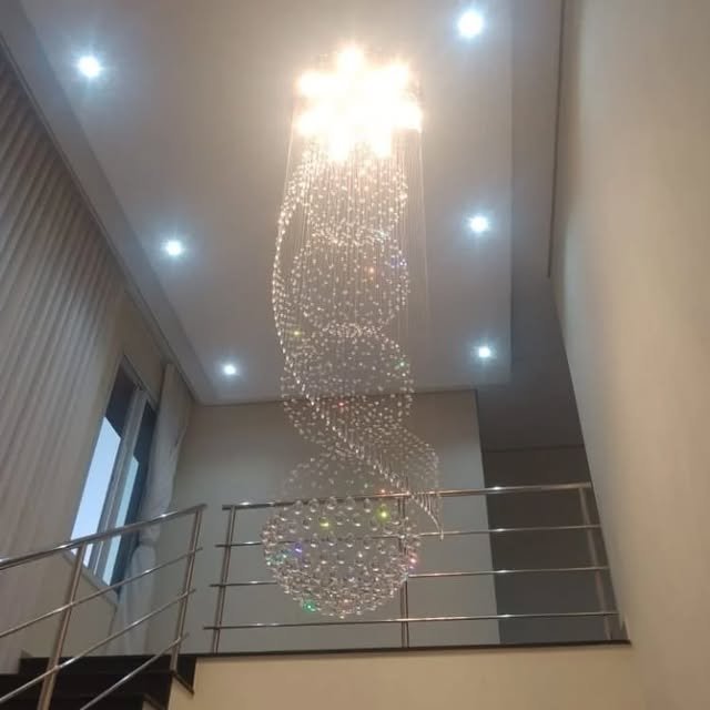 Lustre de cristal em espiral instalado sobre escada, com spots de teto