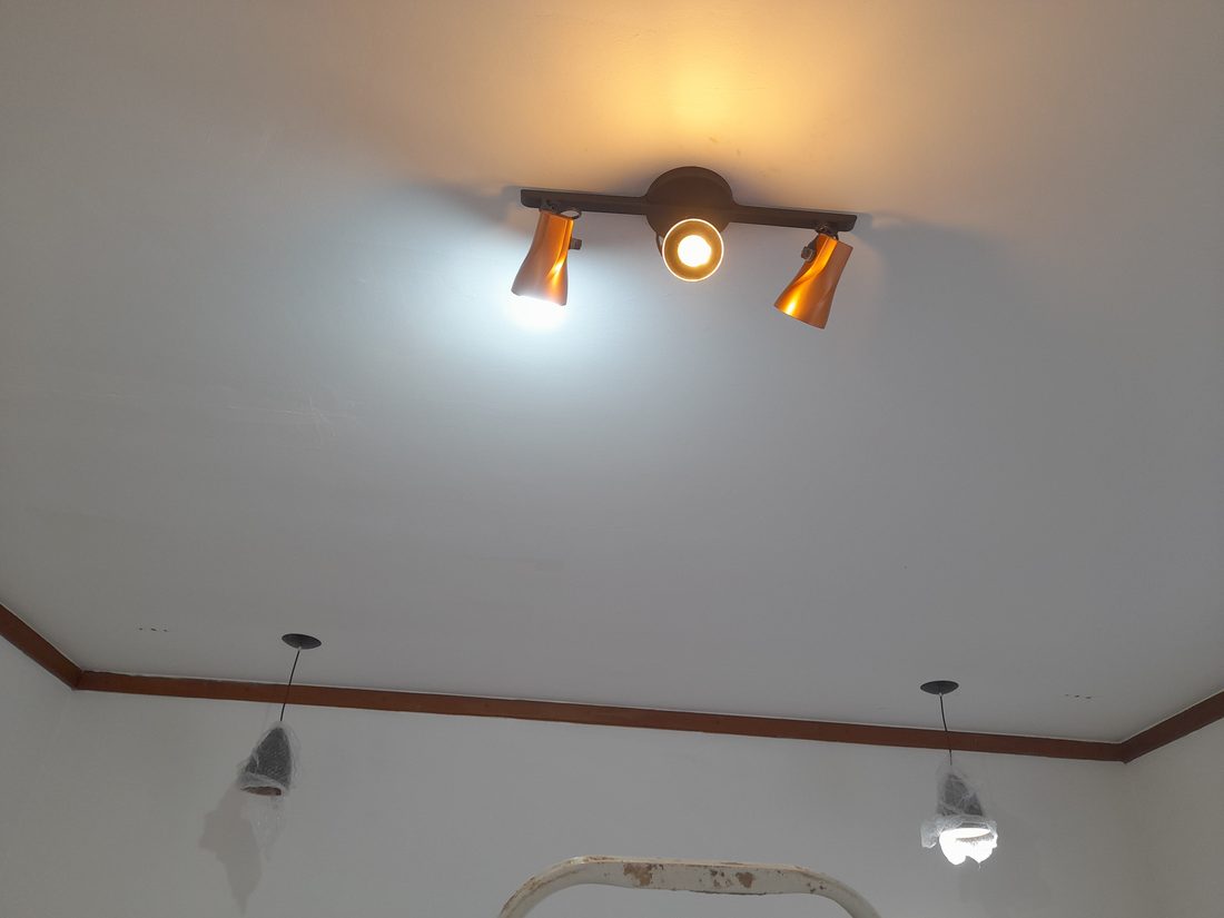 Spot de teto instalado, com luminárias pendentes em fase de montagem ao fundo